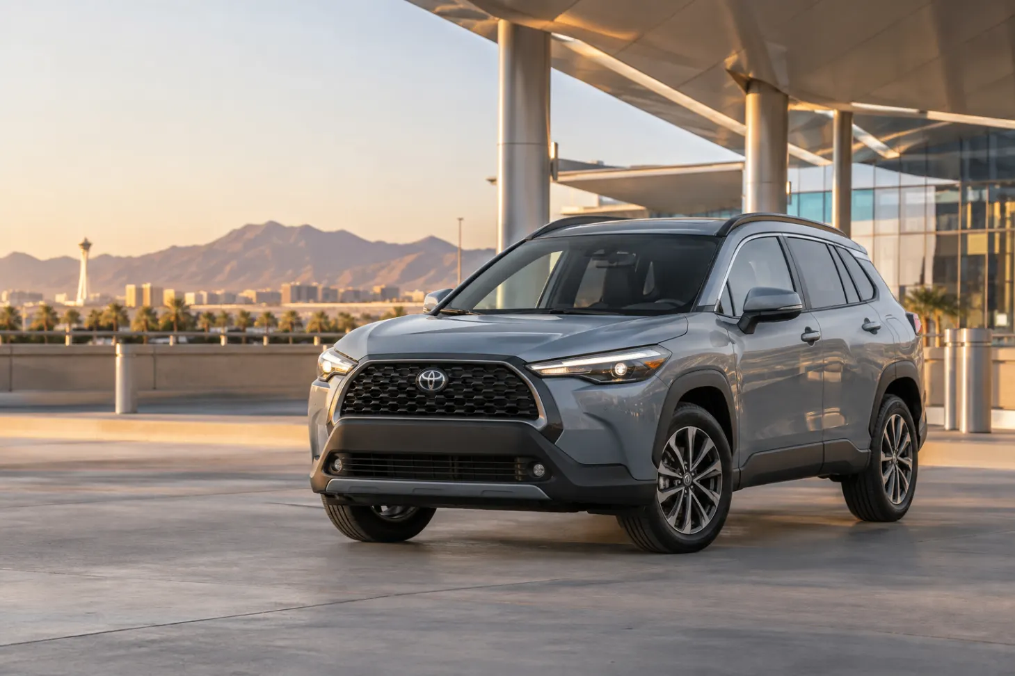 Gray 2026–2027 Toyota Corolla Cross Compact SUV at an airport terminal at golden hour with the Las Vegas skyline behind